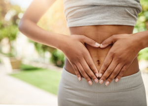 a woman with her hand on her stomach, making the shape of a heart